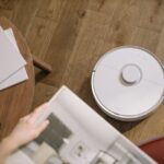 Een moderne robotstofzuiger die zelfstandig door een woonkamer rijdt en stof verzamelt.